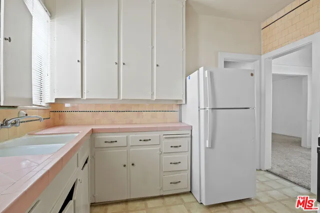 a kitchen with white cabinets and refrigerator