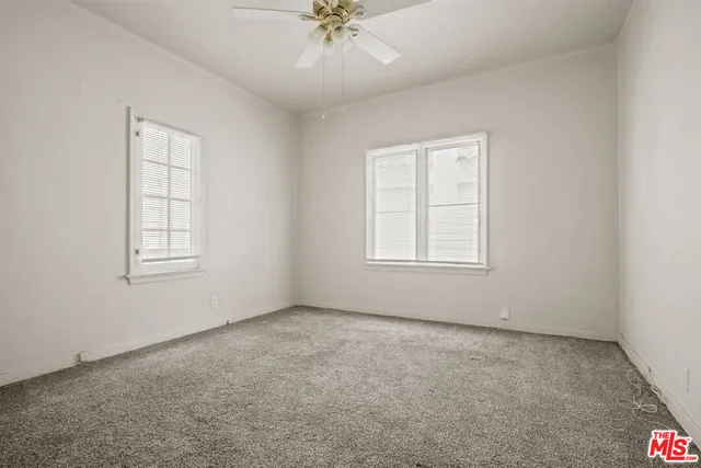 an empty room with a window and a ceiling fan