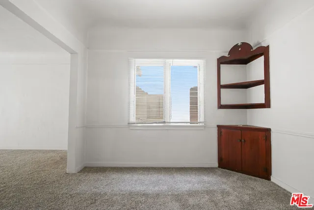 a view of an empty room with window and cabinet