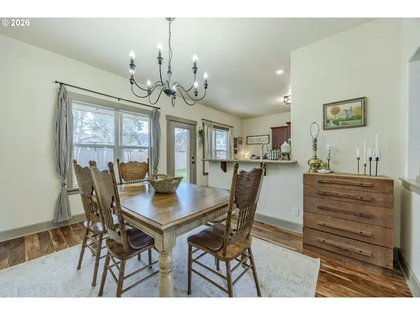 a dining room with wooden floor a chandelier a wooden table and chairs