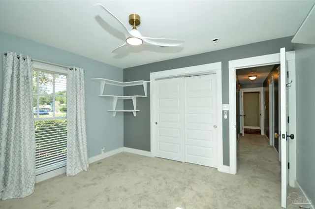 an empty room with closet and a chandelier fan