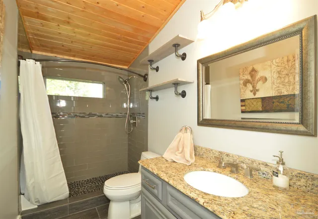 a bathroom with a granite countertop sink toilet and shower