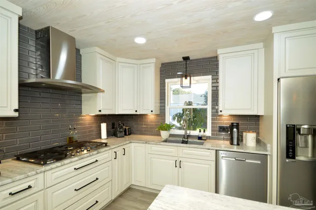 a kitchen with granite countertop a sink stainless steel appliances and cabinets
