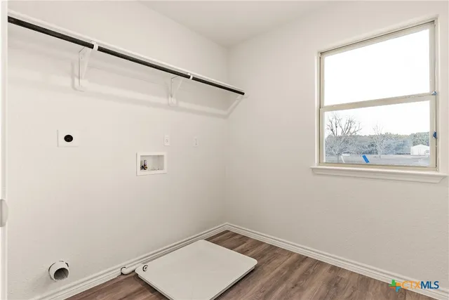 an empty room with wooden floor chandelier fan and windows