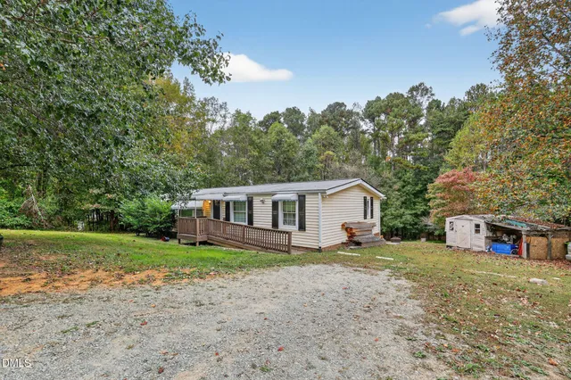 a view of a house with a yard and large trees