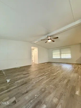 a view of an empty room with window and wooden floor