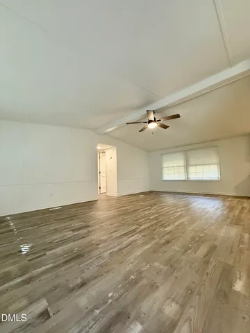 a view of an empty room with window and wooden floor