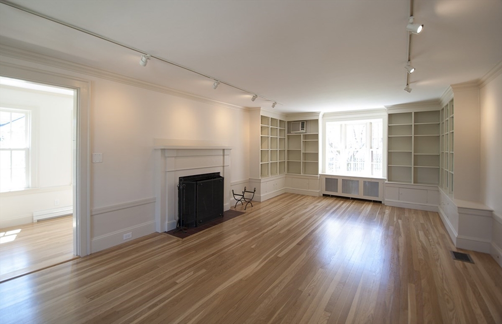 153 Watson Road Belmont, MA 02478 - Photo 2 of 20 an empty room with wooden floor fireplace and windows