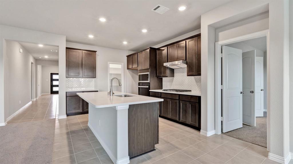 2106 Sandpiper Way Princeton, TX 75407 - Photo 8 of 39 a large kitchen with stainless steel appliances kitchen island granite countertop a large counter top and stove top oven with wooden floor