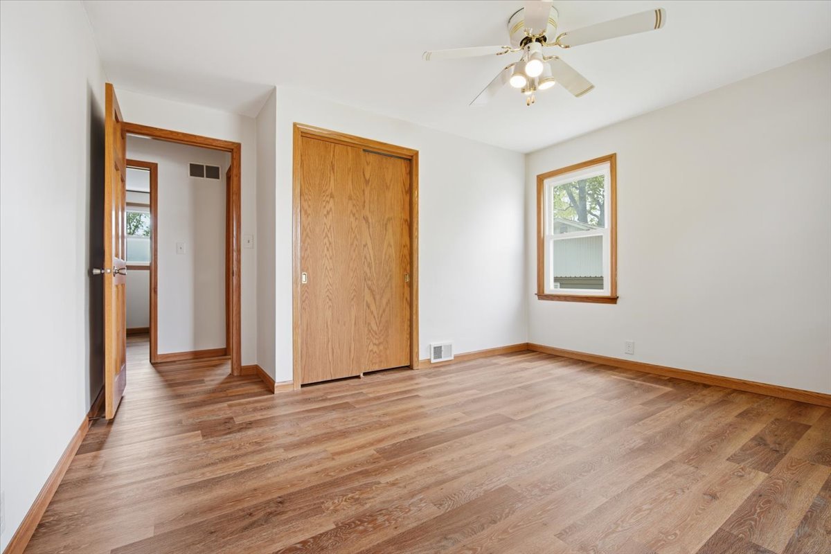509 Smith Street Roanoke, IL 61561 - Photo 15 of 28 an empty room with wooden floor chandelier fan and windows