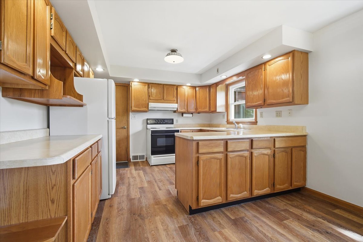 509 Smith Street Roanoke, IL 61561 - Photo 7 of 28 a kitchen with kitchen island granite countertop wooden floors stainless steel appliances a sink and a window