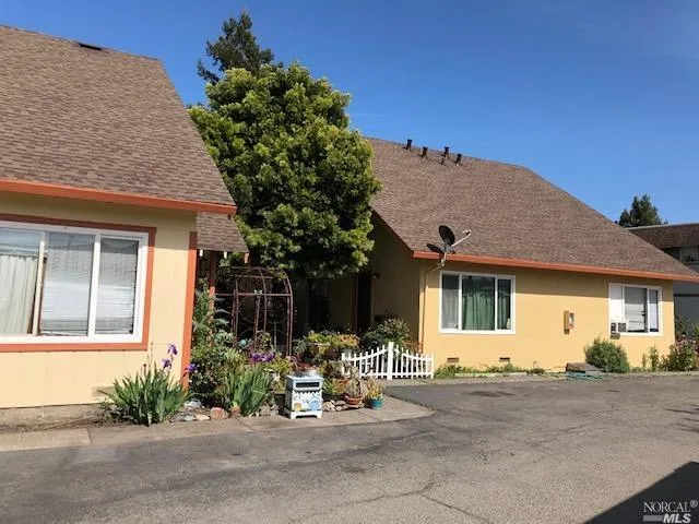 front view of a house with table and chairs under an umbrella
