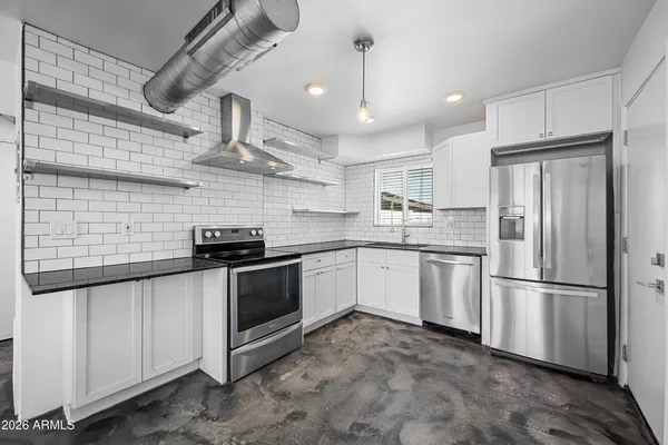 a kitchen with stainless steel appliances granite countertop a sink a stove a refrigerator and cabinets