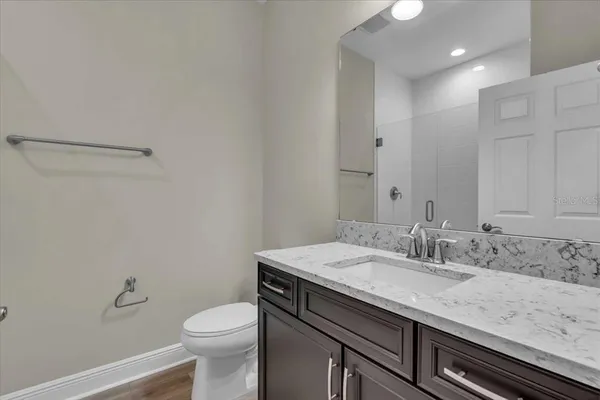 a bathroom with a granite countertop sink a toilet and a mirror