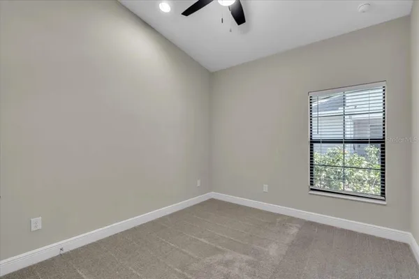 an empty room with a window and a ceiling fan