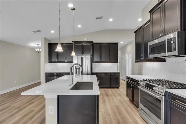 a kitchen with stainless steel appliances a sink a stove top oven a counter space and cabinets