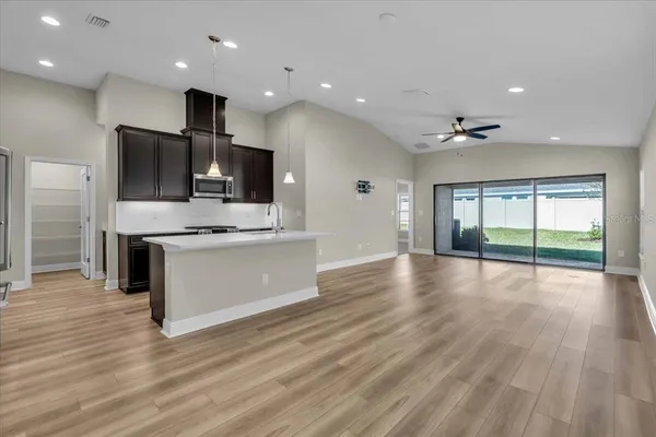 a large kitchen with stainless steel appliances a large counter top and a wooden floor