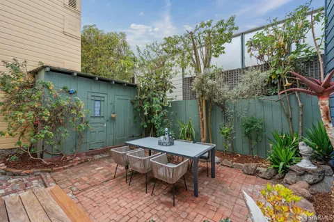 a living room with stainless steel appliances furniture a clock and a view of kitchen