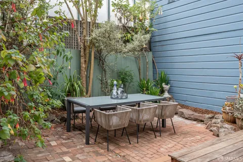 a kitchen with kitchen island granite countertop a dining table chairs and white cabinets with wooden floor