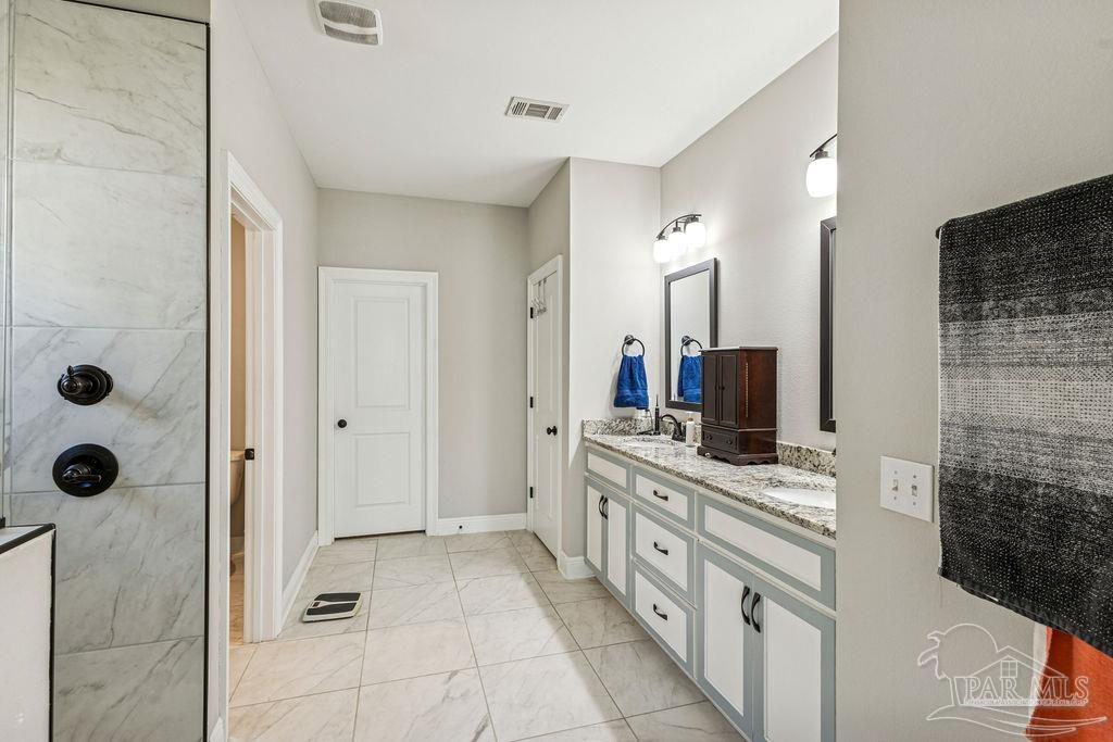 1555 Cadence Loop Cantonment, FL 32533 - Photo 17 of 34 a bathroom with a double vanity sink a mirror and shower