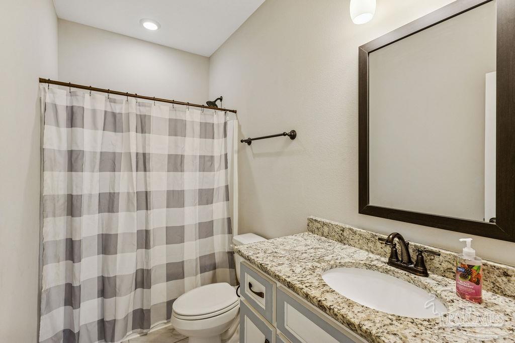 1555 Cadence Loop Cantonment, FL 32533 - Photo 26 of 34 a bathroom with a granite countertop sink toilet a mirror and shower curtain