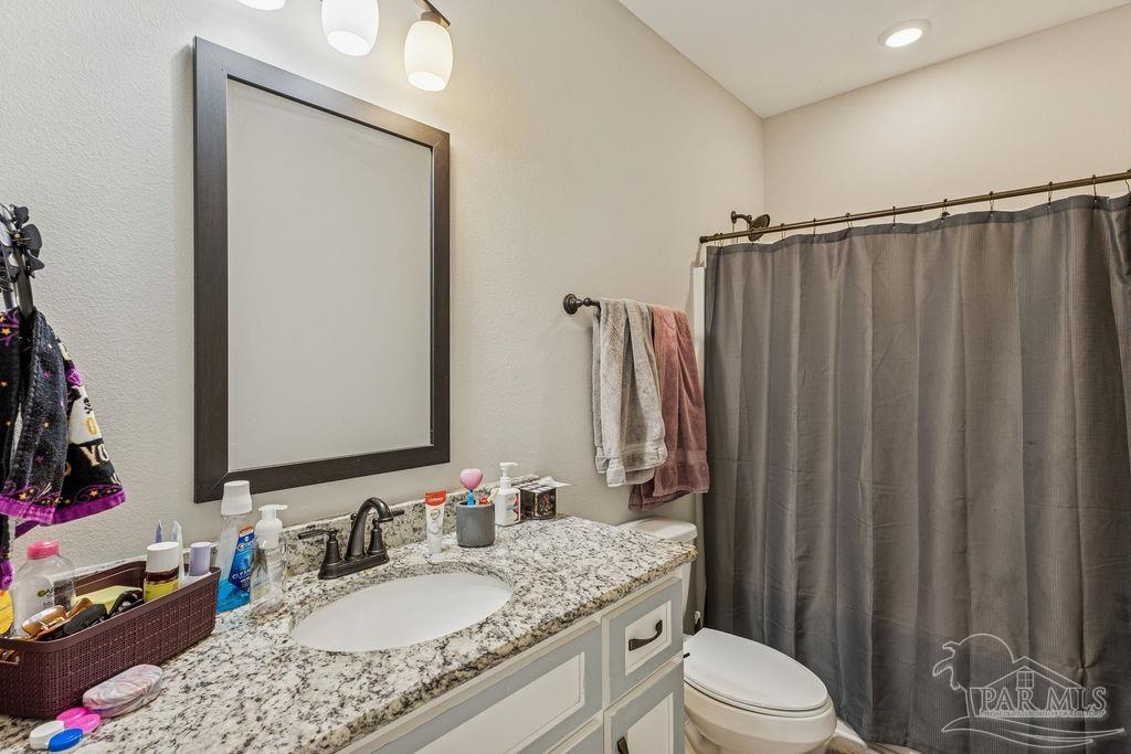 1555 Cadence Loop Cantonment, FL 32533 - Photo 27 of 34 a bathroom with a granite countertop sink toilet and mirror