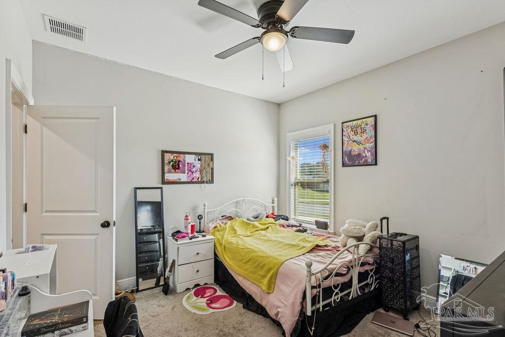 1555 Cadence Loop Cantonment, FL 32533 - Photo 32 of 34 a bedroom with a bed and a chandelier