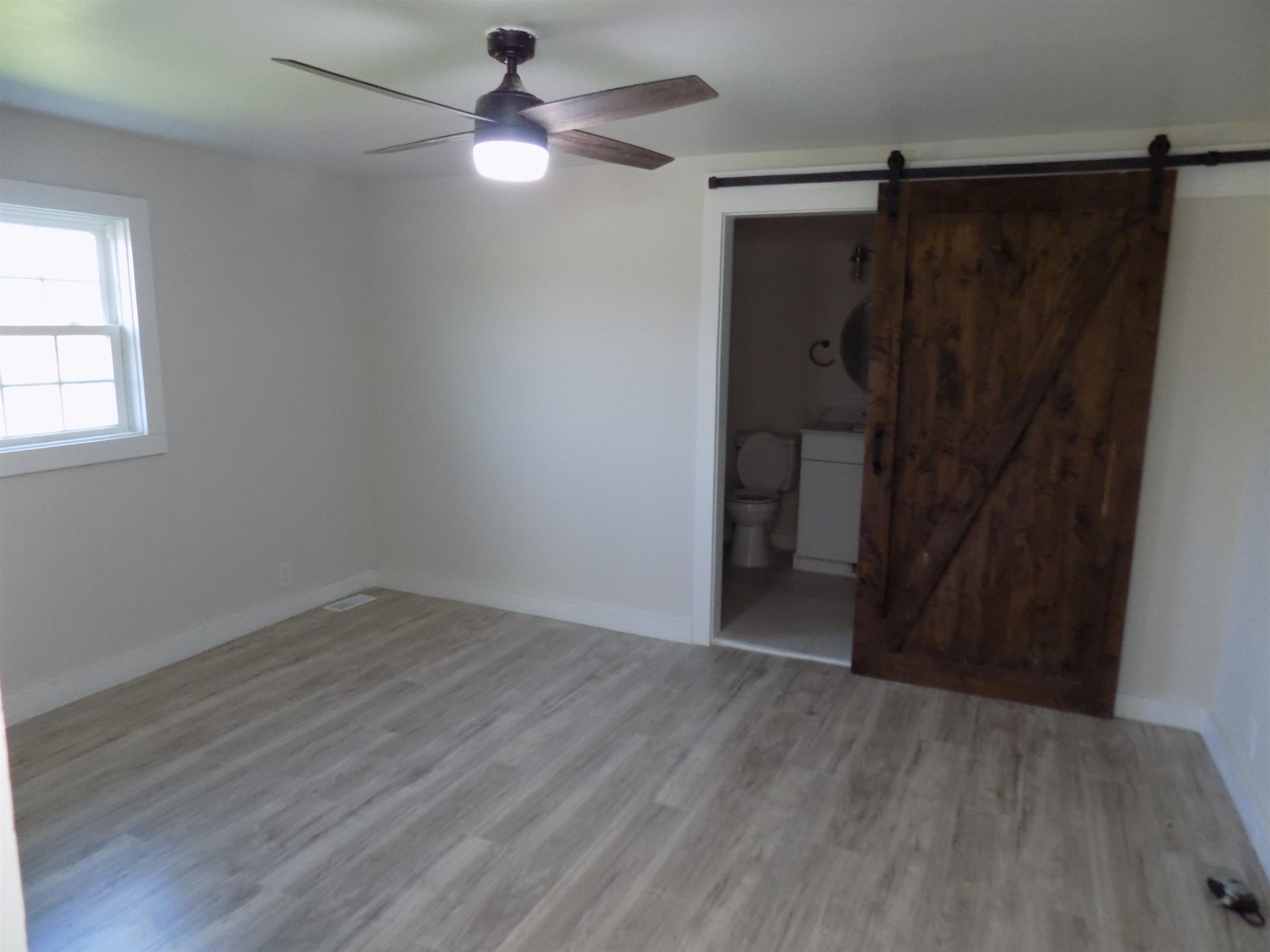 821 Greys Mill Road Louisburg, NC 27549 - Photo 17 of 33 an empty room with wooden floor closet fan and windows