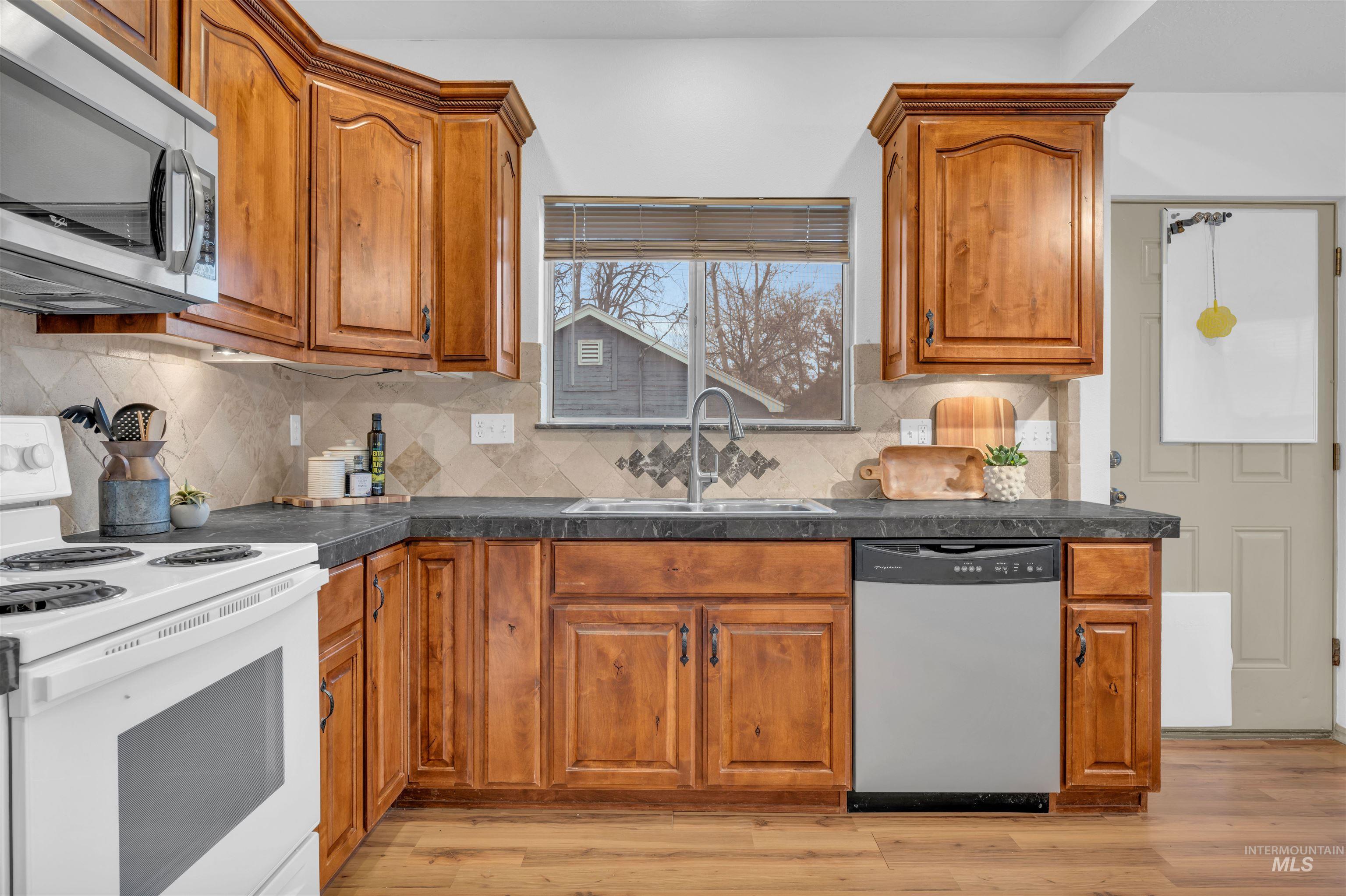 120 South Locust Street Nampa, ID 83686 - Photo 17 of 32 Kitchen with stainless steel appliances, dark countertops, brown cabinets, and light wood-style flooring