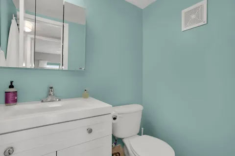 a bathroom with a toilet sink vanity and mirror