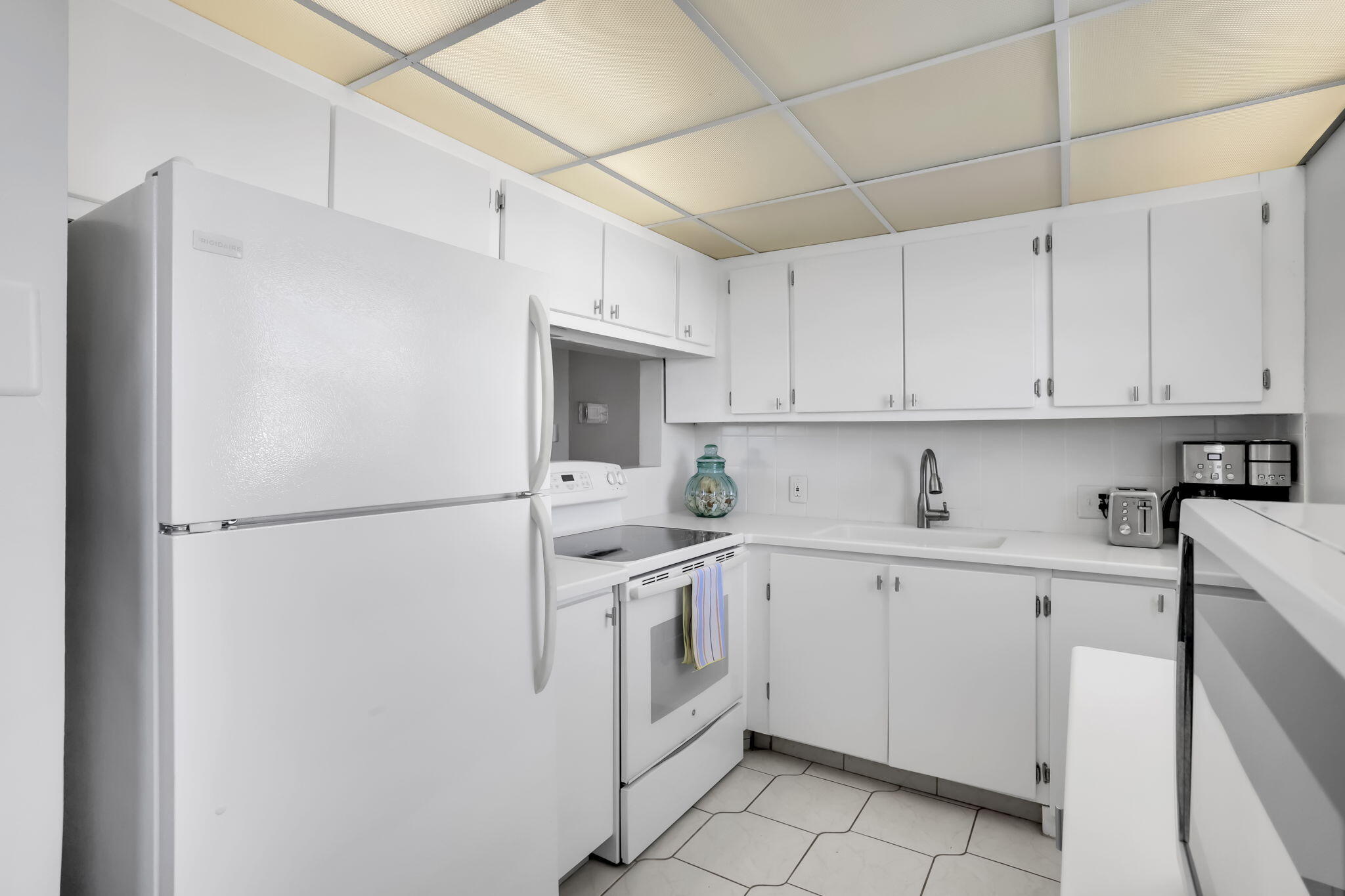 336 Dorset H Boca Raton, FL 33434 - Photo 7 of 31 a kitchen with white cabinets and white appliances