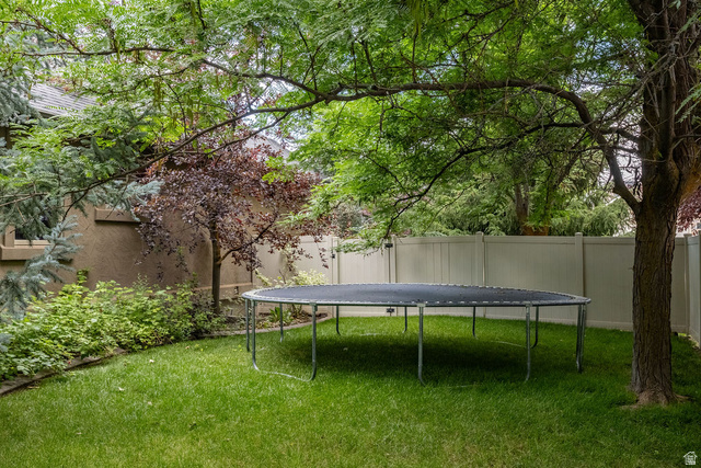 288 525 South Providence, UT 84332 - Photo 64 of 71 Spacious backyard featuring a lush green lawn, mature trees providing natural shade, and a privacy fence