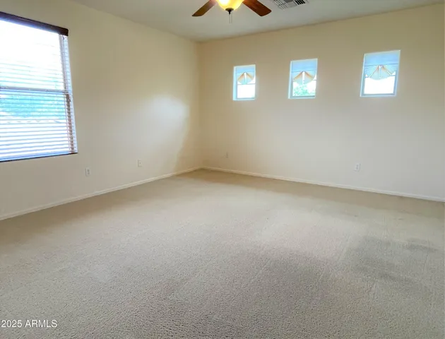 an empty room with windows and chandelier fan