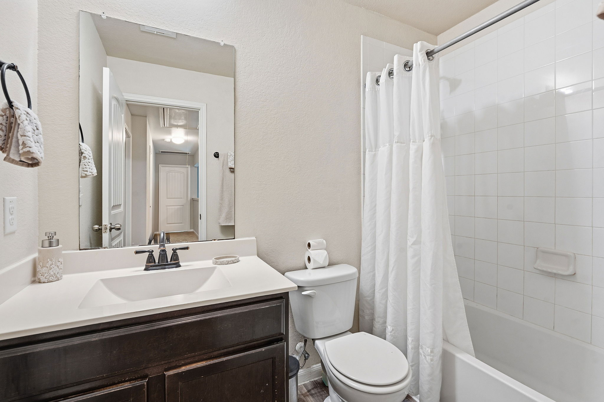 15101 Shell Bark Cove Austin, TX 78724 - Photo 20 of 26 Bathroom featuring a dark wood-finish vanity with an integrated white sink, a chrome-finish faucet, and a large wall-mounted mirror