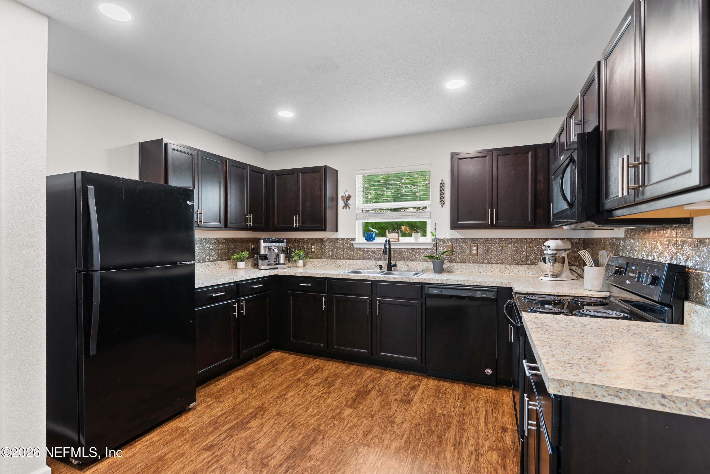 6178 Daylilly Road Macclenny, FL 32063 - Photo 11 of 29 a kitchen with stainless steel appliances granite countertop a refrigerator a sink a stove a microwave and wooden cabinets