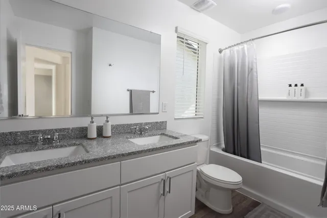 a bathroom with a granite countertop sink mirror vanity and toilet