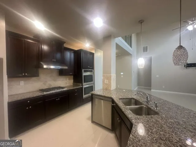 a large kitchen with kitchen island granite countertop a stove a sink and a granite counter tops