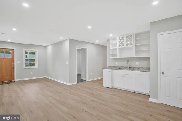 a view of a kitchen with a sink dishwasher a refrigerator with white cabinets and wooden floor
