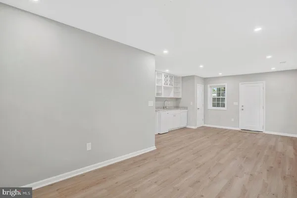 a view of empty room with wooden floor and kitchen