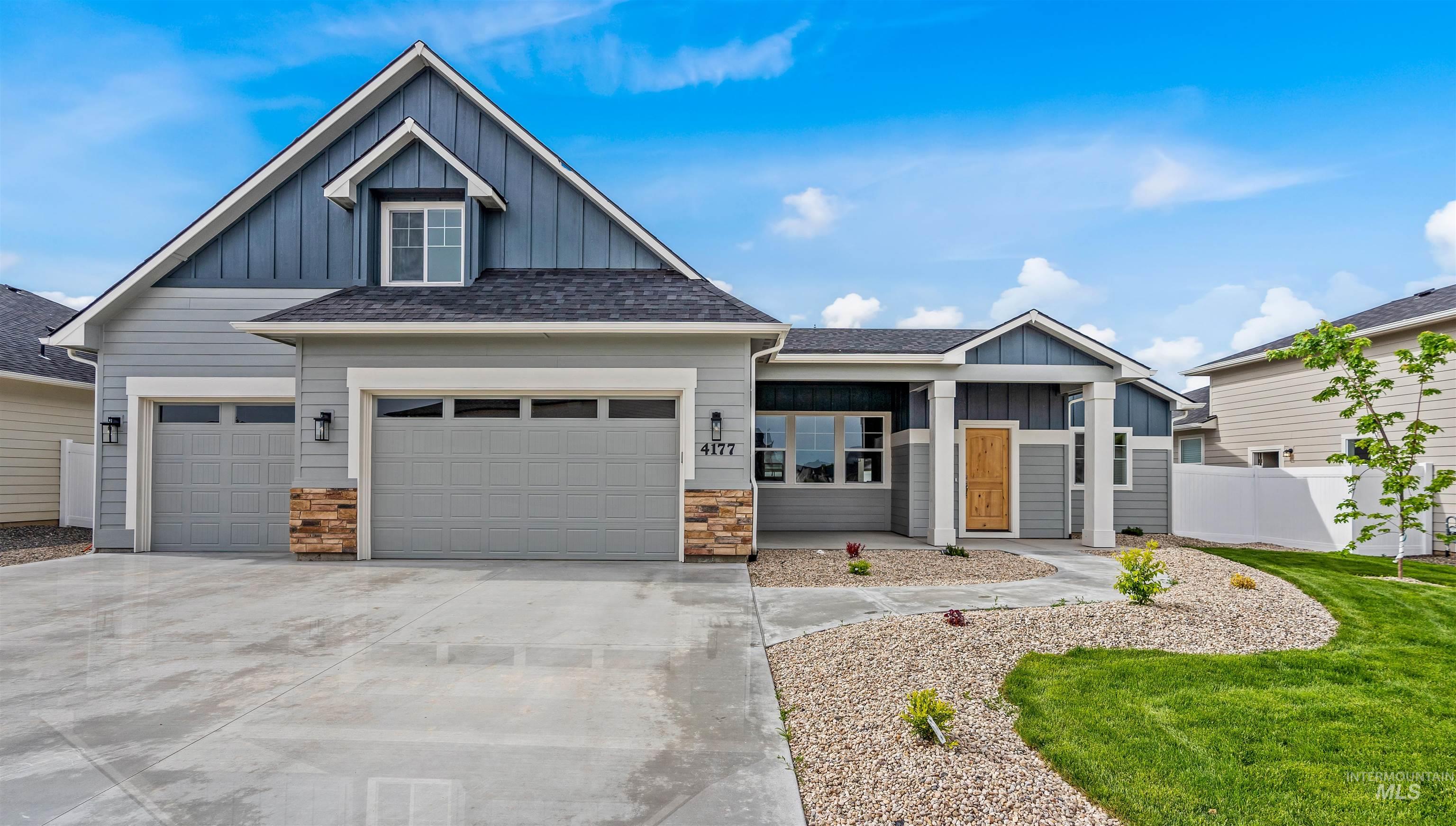 View of front of house with board and batten siding, roof with shingles, driveway, and stone siding