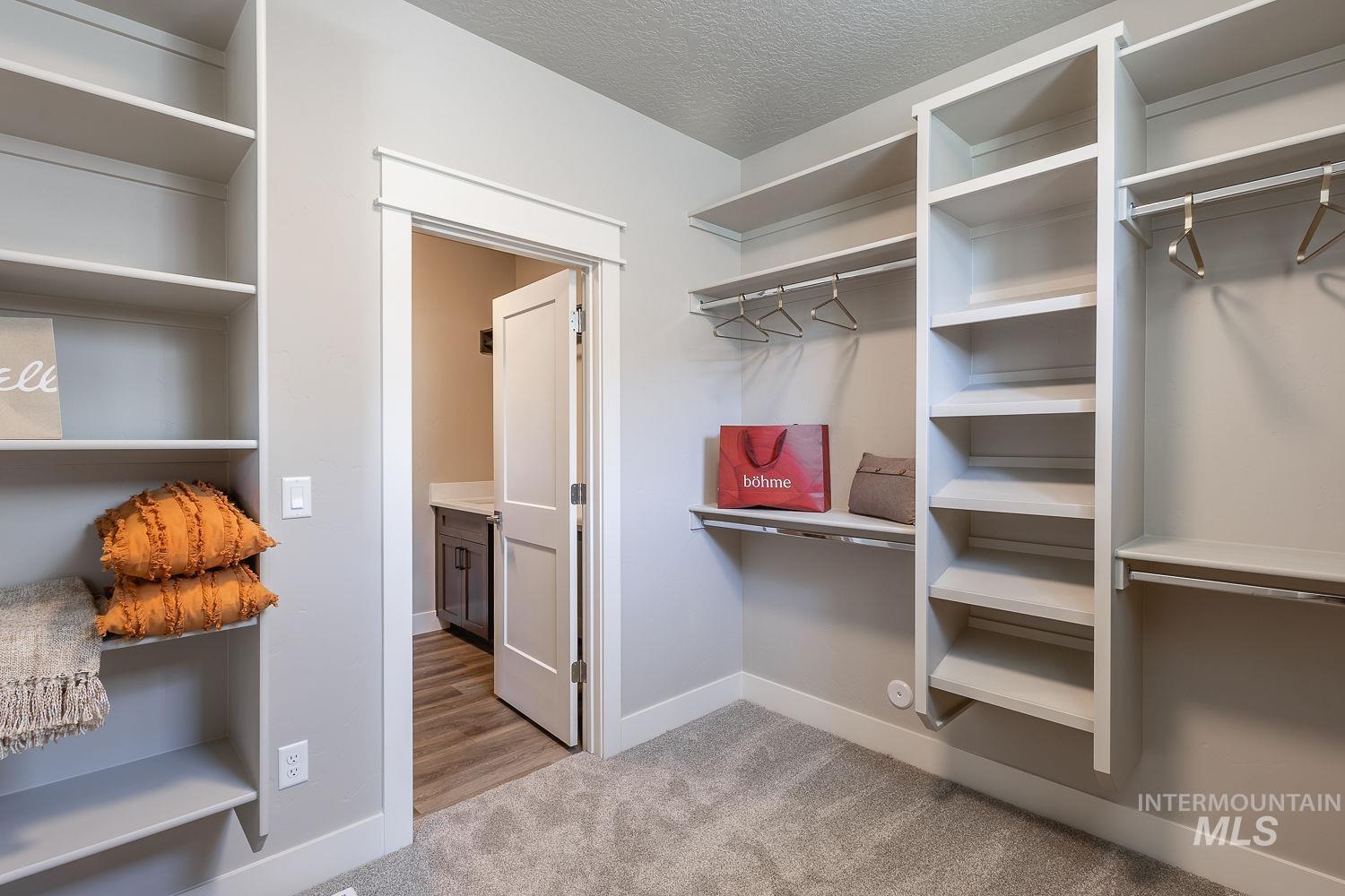 1171 West Recess Way Kuna, ID 83634 - Photo 17 of 28 Spacious walk-in closet featuring built-in shelving, hanging rods, and neutral-toned carpeting