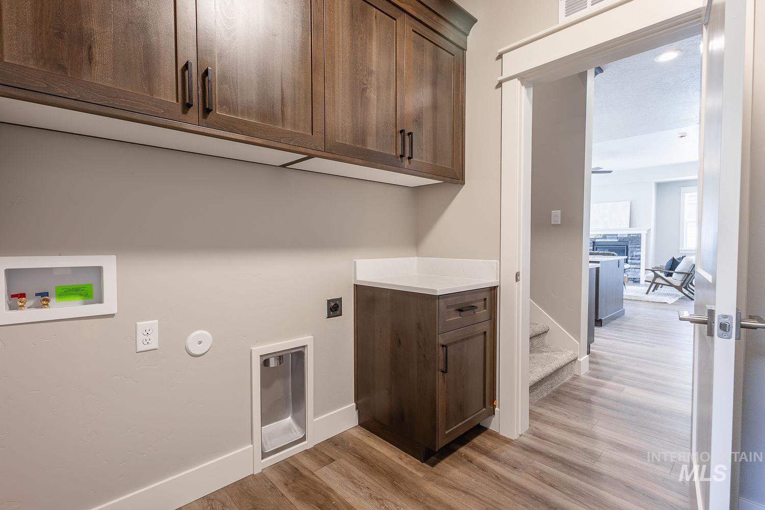1171 West Recess Way Kuna, ID 83634 - Photo 18 of 28 Laundry area featuring wood-finish flooring and extensive upper cabinetry