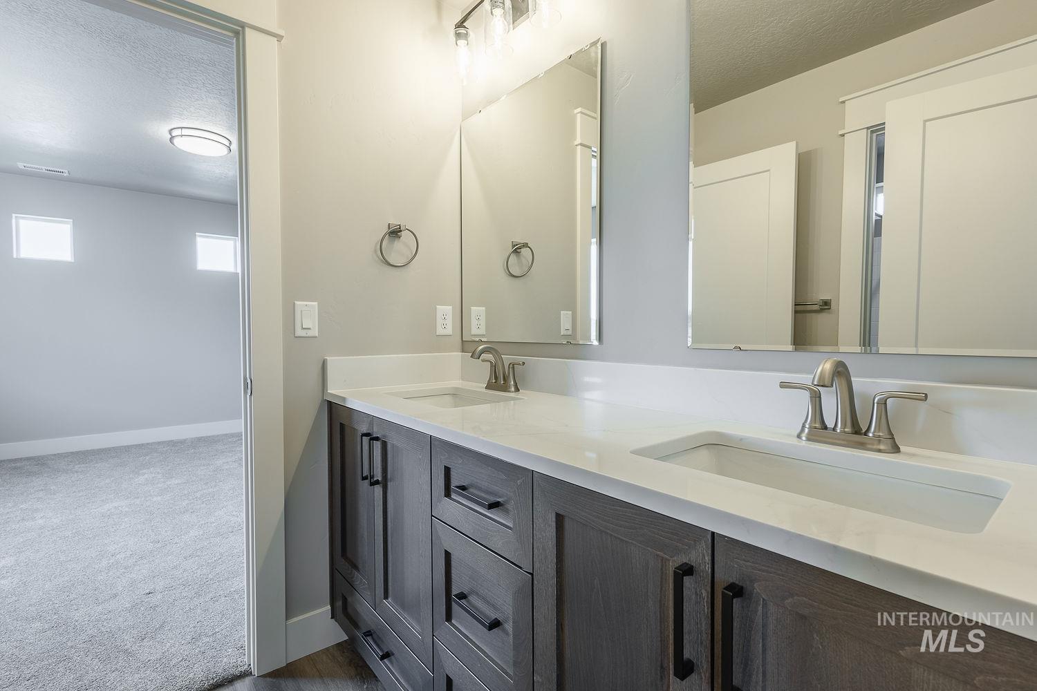 1171 West Recess Way Kuna, ID 83634 - Photo 21 of 28 Double vanity featuring wood-finish cabinetry with black hardware, white countertops, and undermount sinks