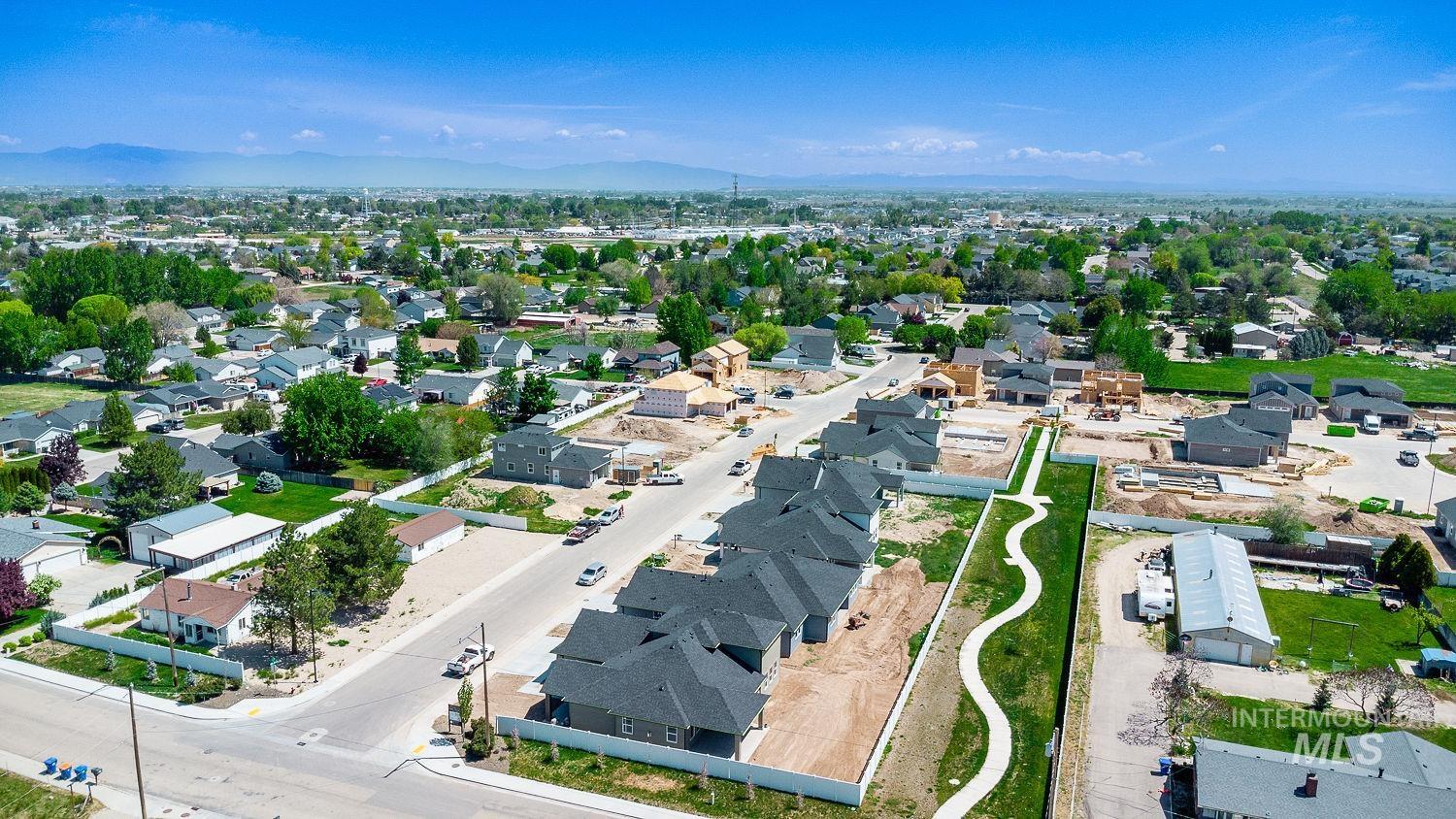 1171 West Recess Way Kuna, ID 83634 - Photo 28 of 28 Developing residential area featuring new construction homes with dark shingle roofs, a paved street, and a concrete walking path through a green space