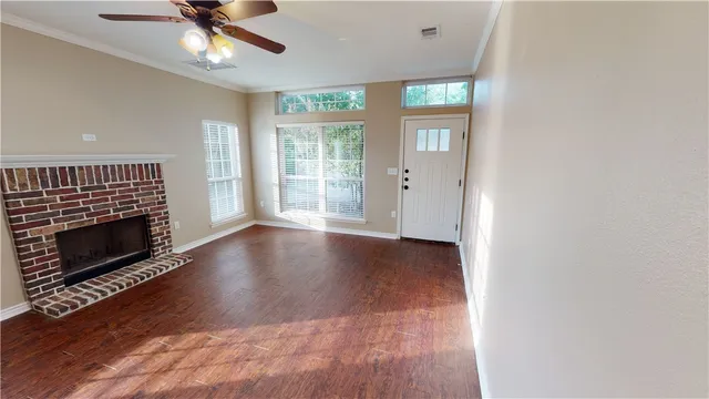 a view of an empty room with wooden floor fireplace and a window