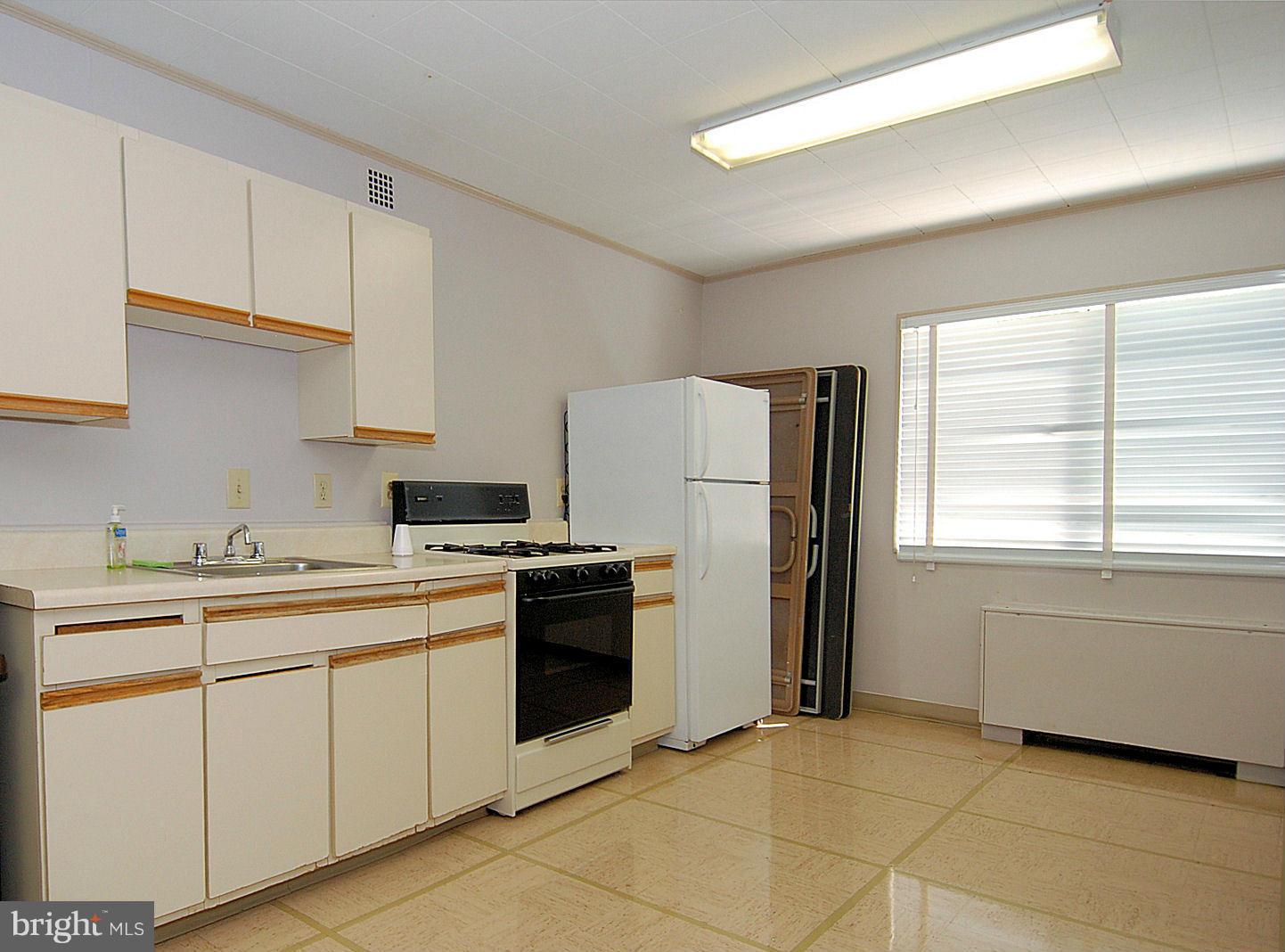 1111 University Boulevard West, Unit 907A Silver Spring, MD 20902 - Photo 10 of 15 a kitchen with a stove a sink and a refrigerator