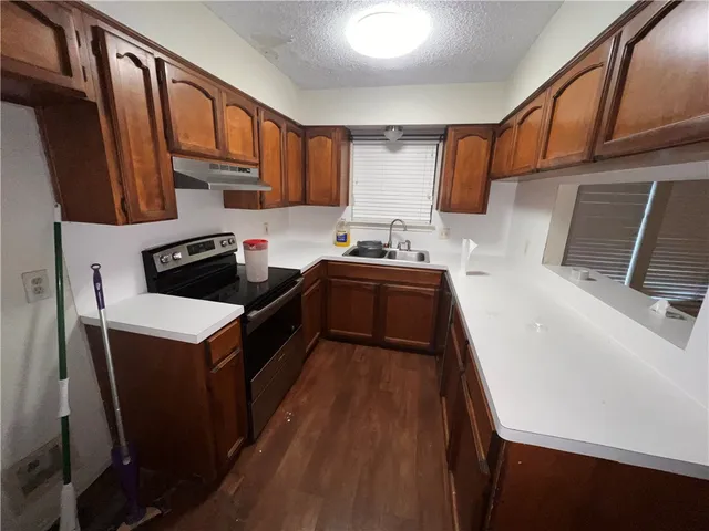 a kitchen with a sink a stove wooden cabinetry and stainless steel appliances