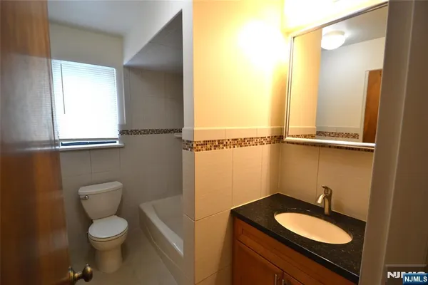 a bathroom with a granite countertop toilet sink and mirror