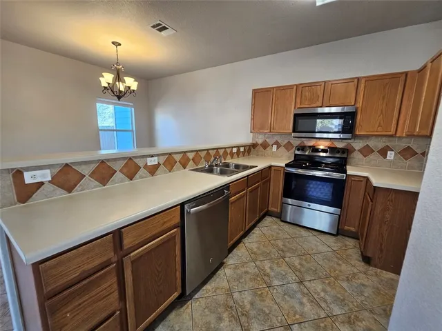 a kitchen with stainless steel appliances granite countertop a sink wooden cabinets and a stove top oven