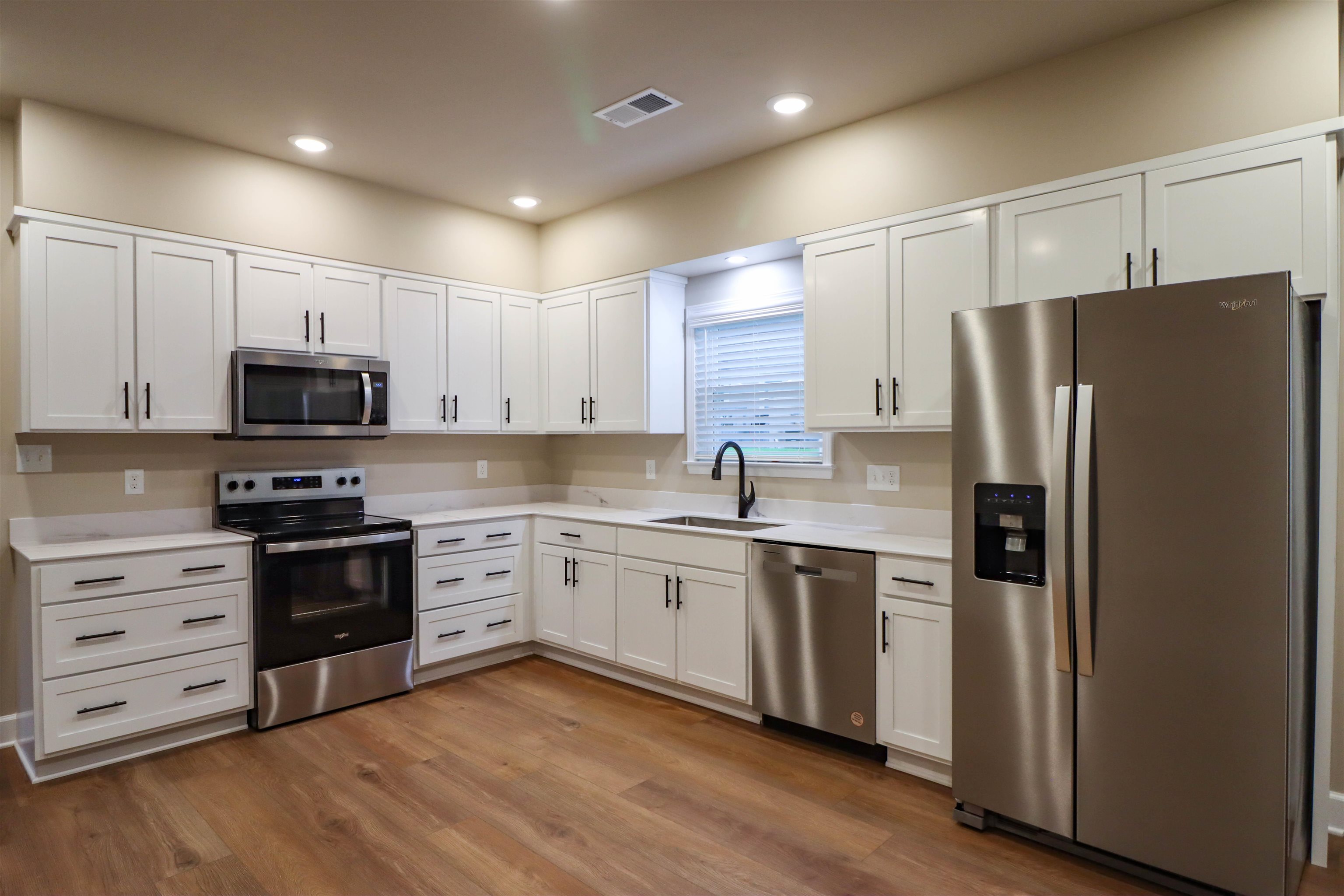 208 Church Street Ripley, TN 38063 - Photo 7 of 33 Kitchen with stainless steel appliances, a sink, light countertops, luxury vinyl floors, and white cabinets